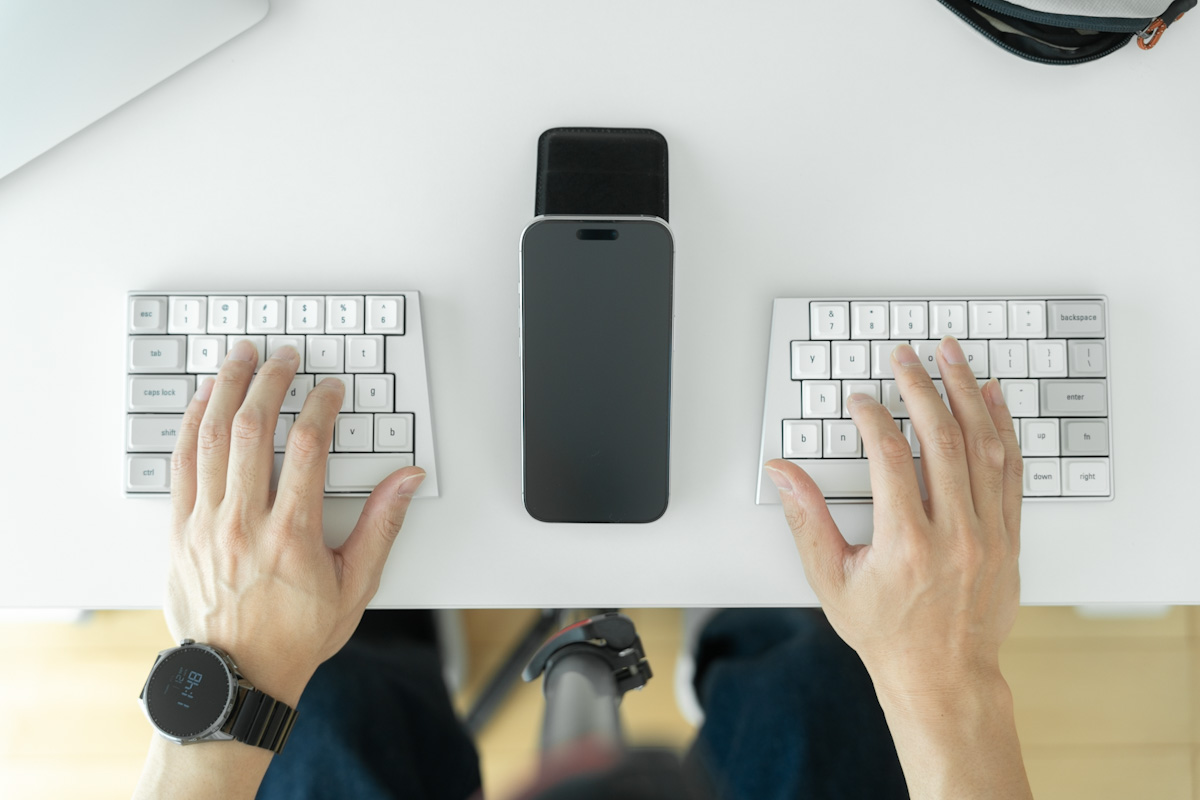 Elytraの左右ユニットの間にスマホを置いてタイピングしているところ